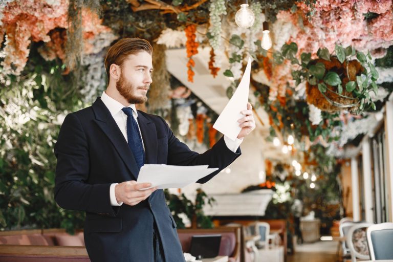A best man giving a wedding speech, or preparing for a wedding speech with a workshop.