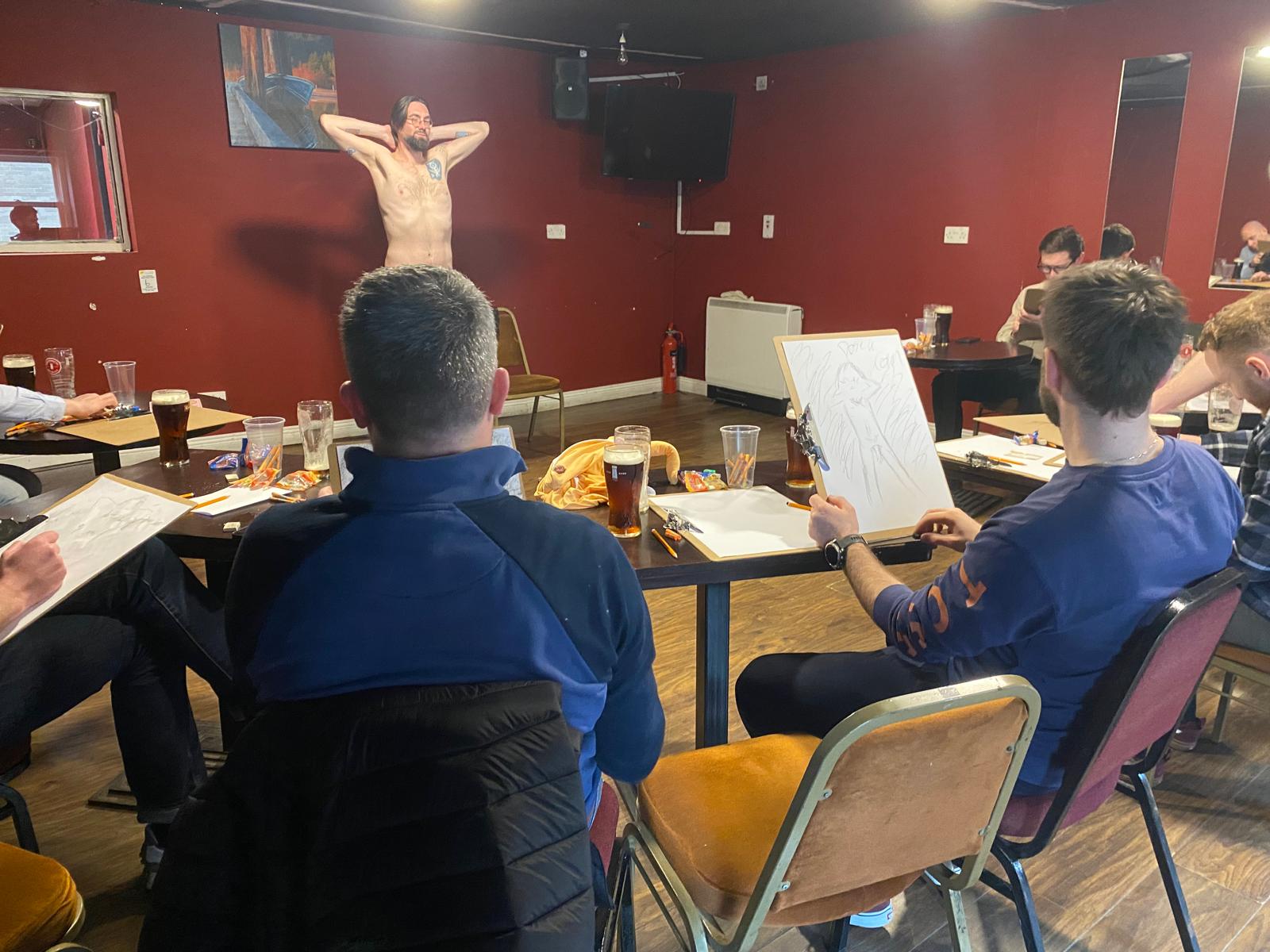 A group participating in the activity "Draw a nude", which is a great group activity for a stag party, hen party, or birthday party.