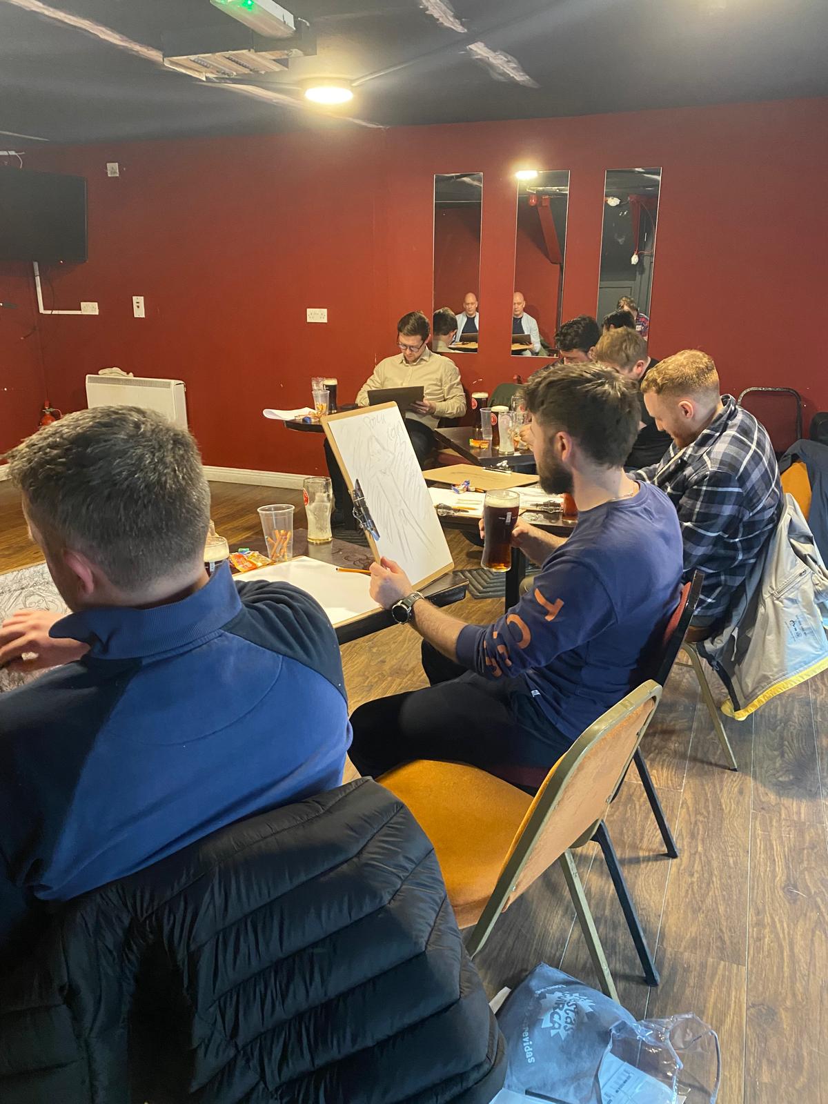 Group of people participating in "Draw A Nude" activity, perfect for stag parties, hen parties, and more.
