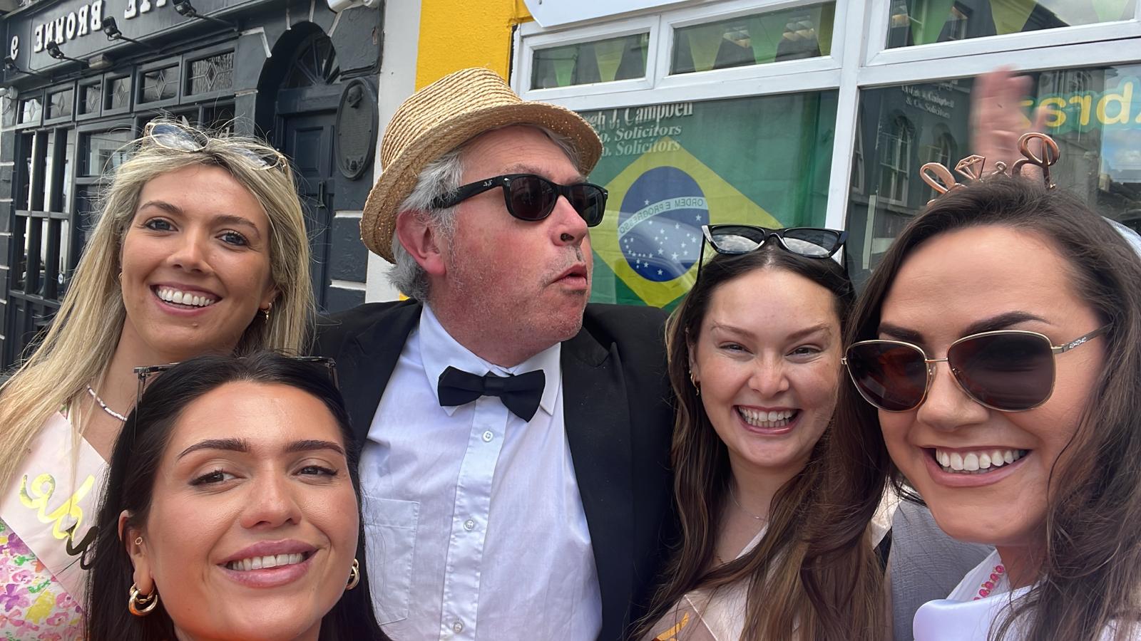 Hen party posing for a photo with an actor after playing an activity such as "Murder Mystery", "The Farmer's Bride", or "Mrs. Doyle's Hen Party"